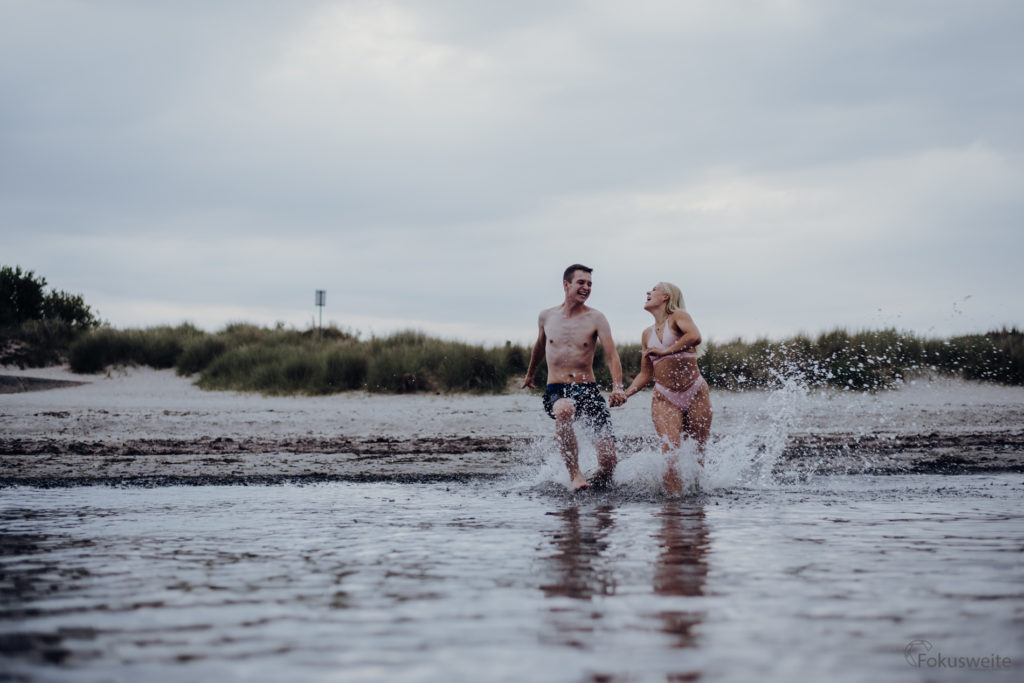 Paarfotografie am Meer - Strand von Grömitz - Paar läuft in die Ostsee